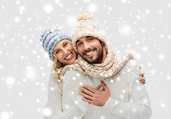 Image showing smiling couple in winter clothes hugging over snow