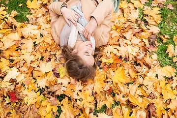 Image showing beautiful happy woman lying on autumn leaves