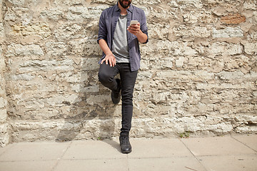 Image showing close up of man with smartphone at stone wall