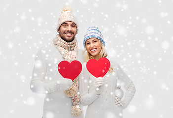 Image showing smiling couple in winter clothes with red hearts