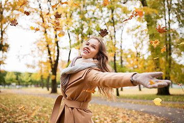 Image showing happy woman having fun with leaves in autumn park