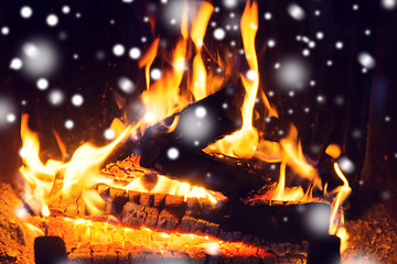 Image showing close up of firewood burning in fireplace and snow