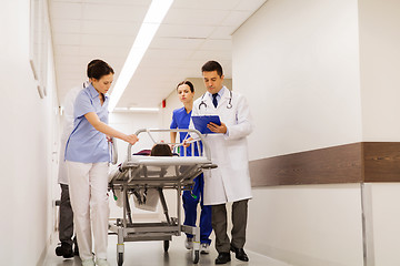 Image showing medics with woman on hospital gurney at emergency