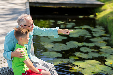 Image showing grandfather and grandson sitting on river berth