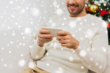 Image showing smiling man with smartphone at home for christmas