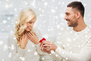 Image showing happy man giving engagement ring to woman at home