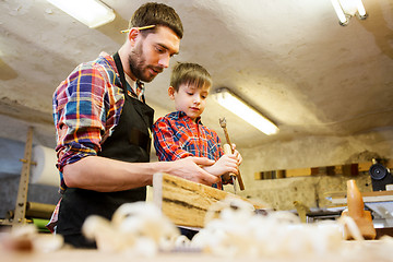 Image showing father and son with chisel working at workshop