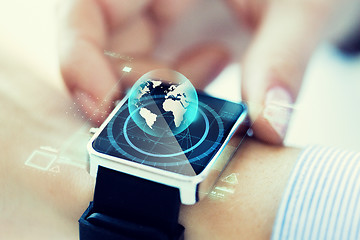 Image showing close up of hand with globe hologram on smartwatch