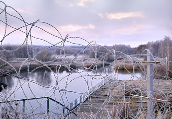 Image showing Post a fence of barbed wire in winter in frost at dawn