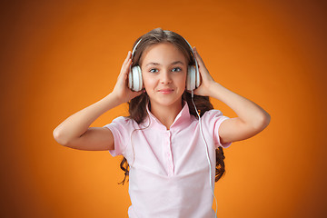 Image showing The cute cheerful little girl on orange background