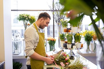 Image showing smiling florist man making bunch at flower shop