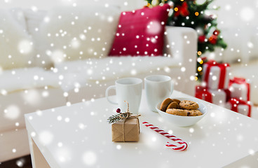 Image showing close up of gift, sweets and cups on table at home