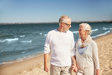 Image showing happy senior couple walking along summer beach