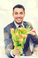 Image showing smiling handsome man giving bouquet of flowers