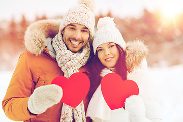 Image showing happy couple with red hearts over winter landscape