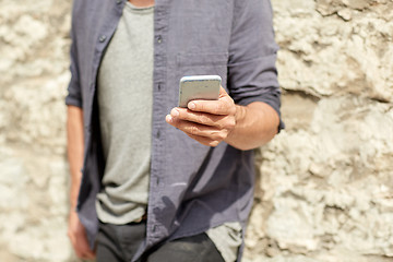 Image showing close up of man with smartphone at stone wall