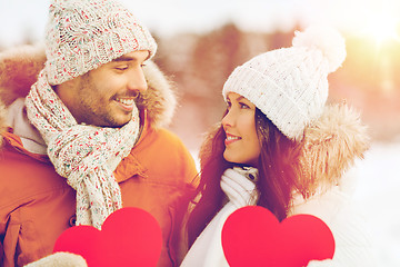 Image showing happy couple with red hearts over winter landscape