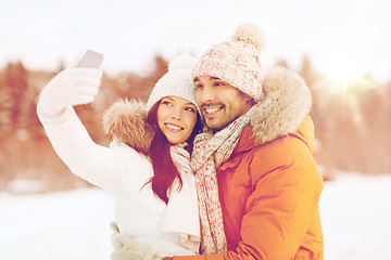 Image showing happy couple taking selfie by smartphone in winter