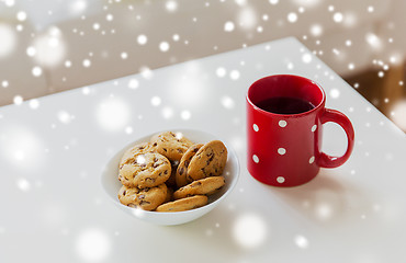 Image showing close up of oat cookies and red tea cup on table