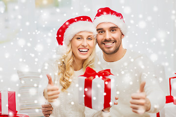 Image showing happy couple with christmas gifts and thumbs up