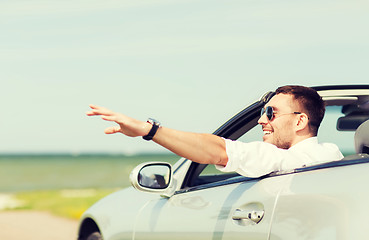 Image showing happy man driving cabriolet car and waving hand