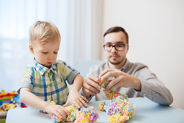 Image showing father and son playing with ball clay at home