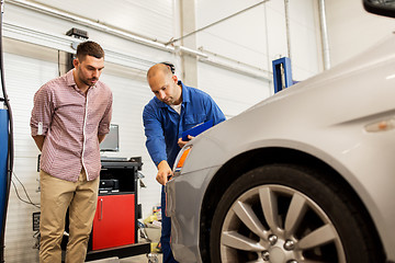 Image showing auto mechanic with clipboard and man at car shop