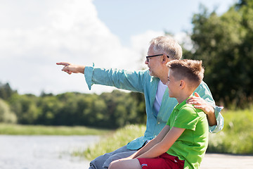 Image showing grandfather and grandson sitting on river berth