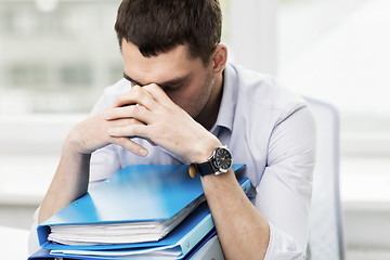 Image showing sad businessman with stack of folders at office