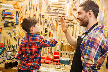 Image showing father and little son making high five at workshop