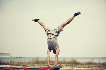 Image showing young man exercising on bench outdoors