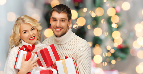 Image showing happy couple in sweaters holding christmas gifts