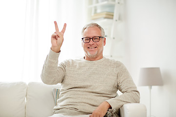 Image showing smiling senior man showing v sign at home