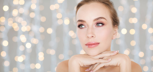 Image showing beautiful young woman face and hands over lights