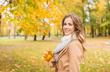 Image showing beautiful woman with maple leaves in autumn park