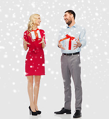 Image showing happy couple with christmas gift boxes over snow