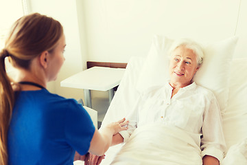 Image showing doctor or nurse visiting senior woman at hospital