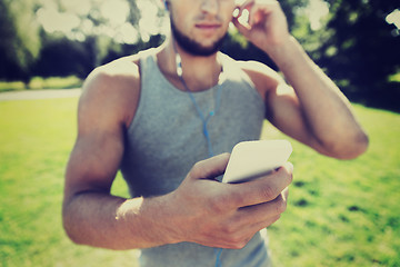 Image showing young man with earphones and smartphone at park