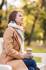 Image showing happy young woman drinking coffee in autumn park