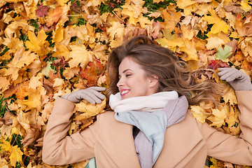 Image showing beautiful happy woman lying on autumn leaves