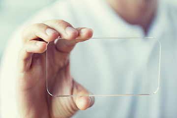 Image showing close up of male hand with transparent smartphone