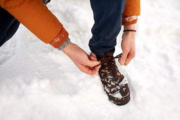 Image showing close up of man tying boot shoelaces in winter