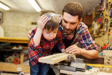 Image showing father and little son with wood plank at workshop