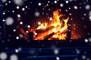 Image showing close up of firewood burning in fireplace and snow