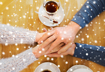 Image showing close up of couple holding hands at restaurant