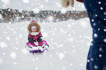 Image showing parent carrying happy little kid on sled in winter