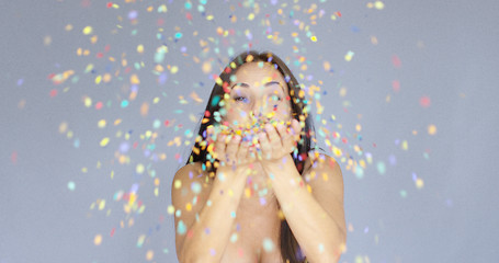 Image showing Young woman blowing colorful New Year confetti