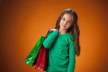 Image showing The cute cheerful little girl with shopping bags