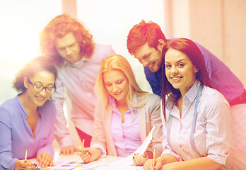 Image showing smiling creative team looking over clothes designs