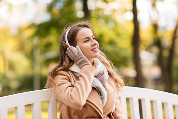 Image showing happy woman with headphones in autumn park